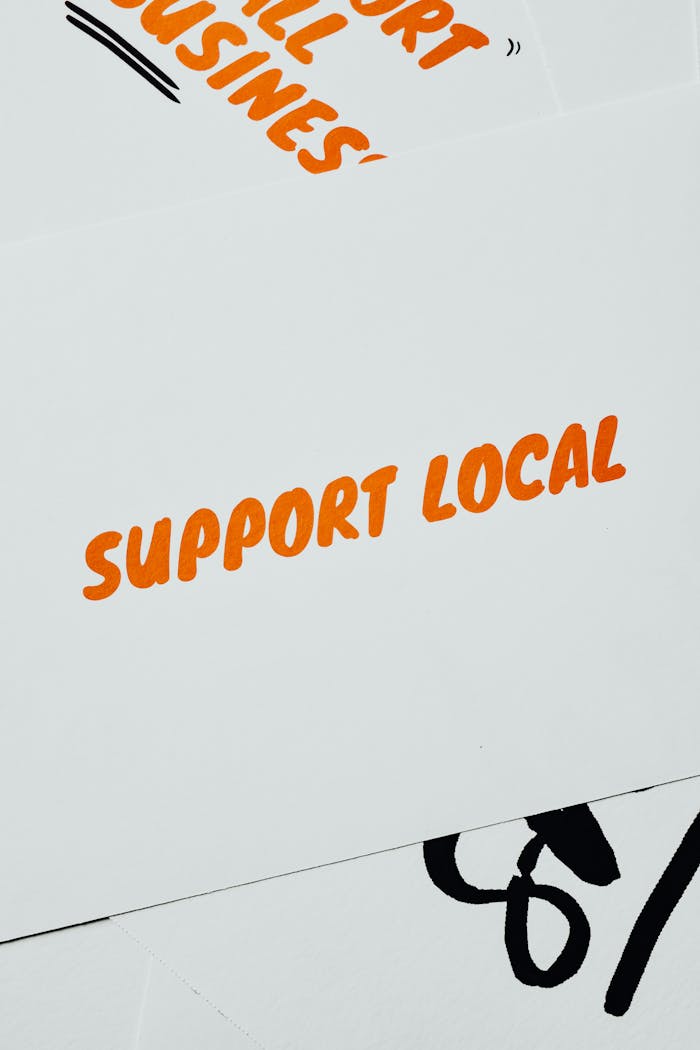 A minimalist card displaying 'Support Local' in bold orange text on a white background, promoting small businesses.